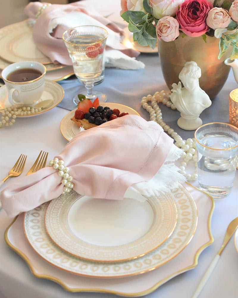 A tablesetting with pink-and-white china and pearl accents.