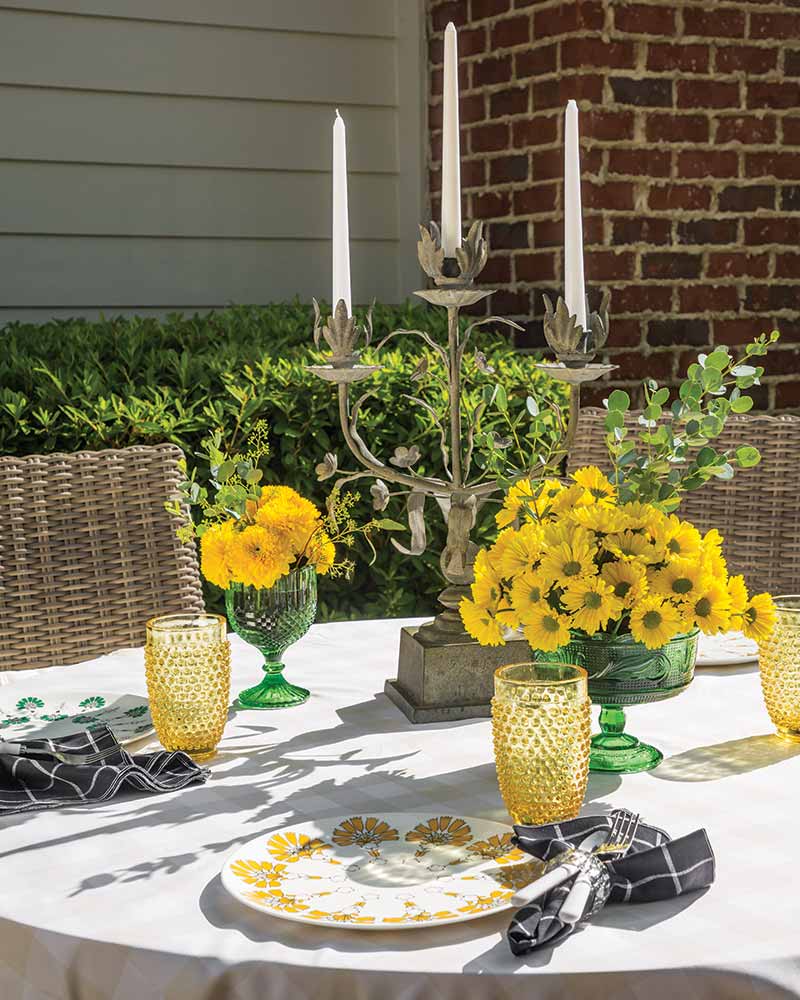 An alfresco tablescape with yellow flowers and dishware.