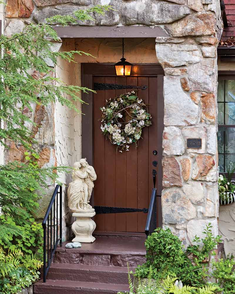 A stone house with a white floral wreath on the front door.