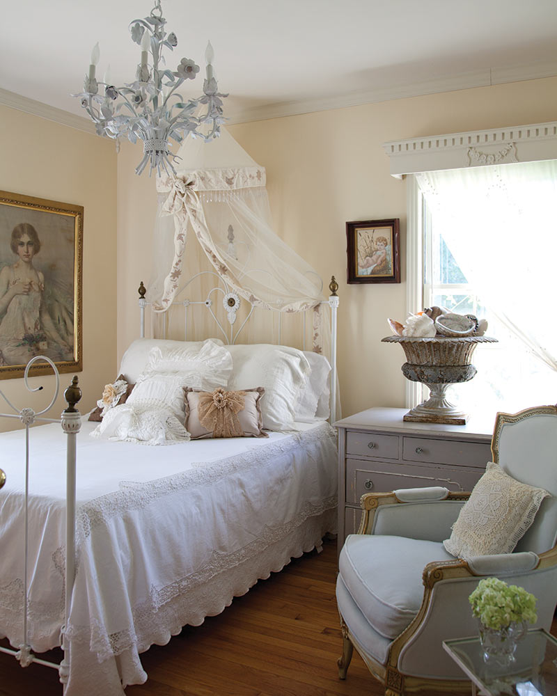 A white metal bed dressed with white vintage linens.