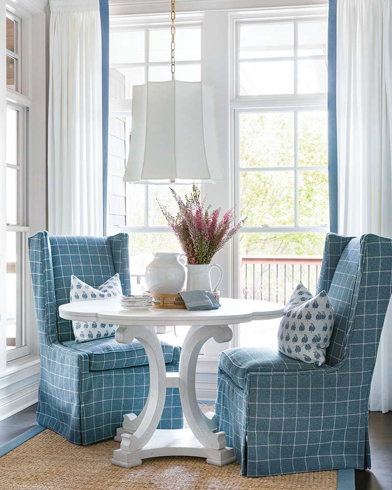 A breakfast nook with blue wingback chairs.