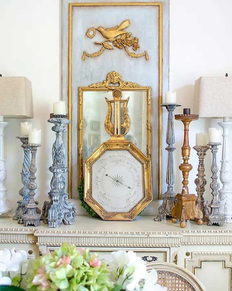 A tabletop vignette with French antique candlesticks and an octagonal barometer.