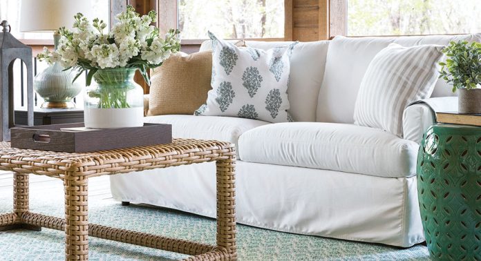A slipcovered sofa and rattan coffee table.
