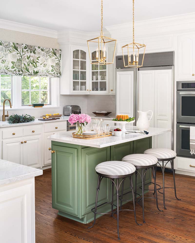 A white kitchen with an island painted sage green.