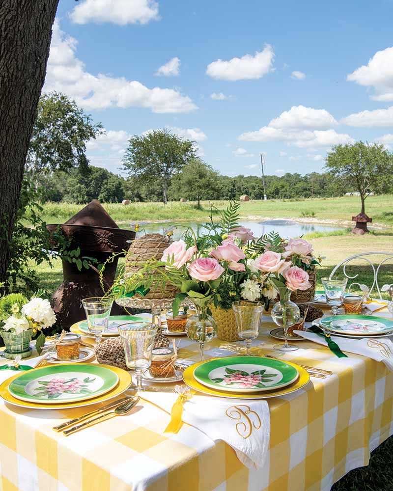 An alfresco table with a yellow checked tablecloth. 