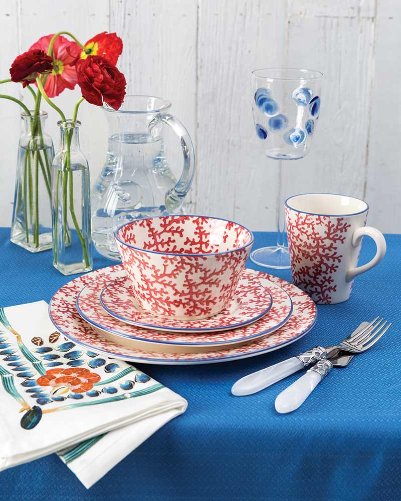 A table set with red-and-white coral dishware.