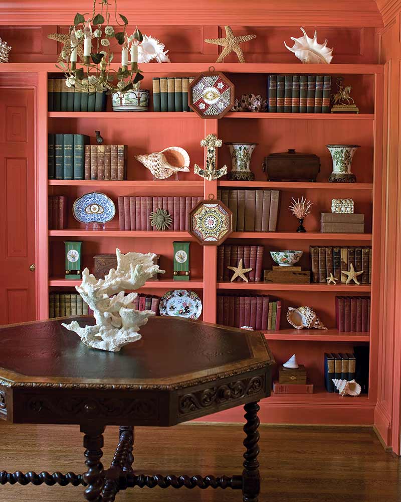 A bookshelf painted coral with coastal accents.