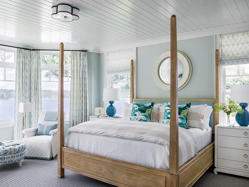 A bedroom painted a light seafoam green with white, sand, and blue textiles.
