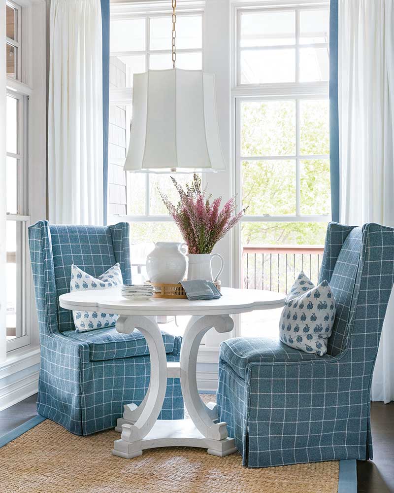 A breakfast nook with a white table and blue-and-white chairs.