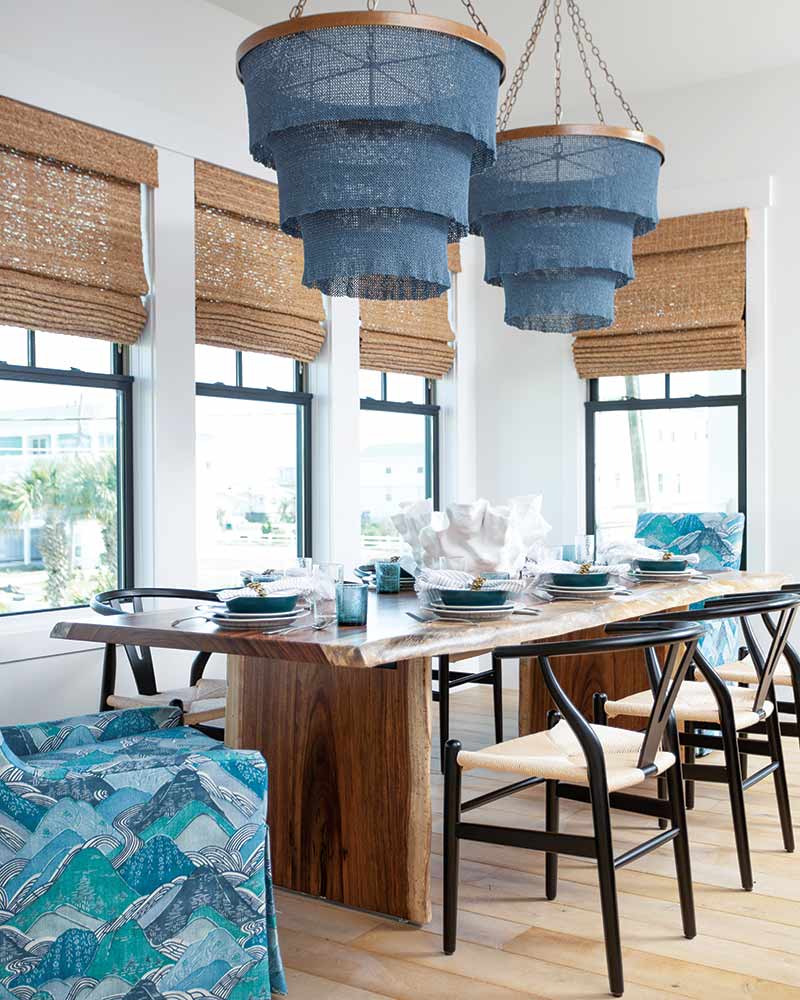 A dining area with blue chandeliers and rattan window treatments.