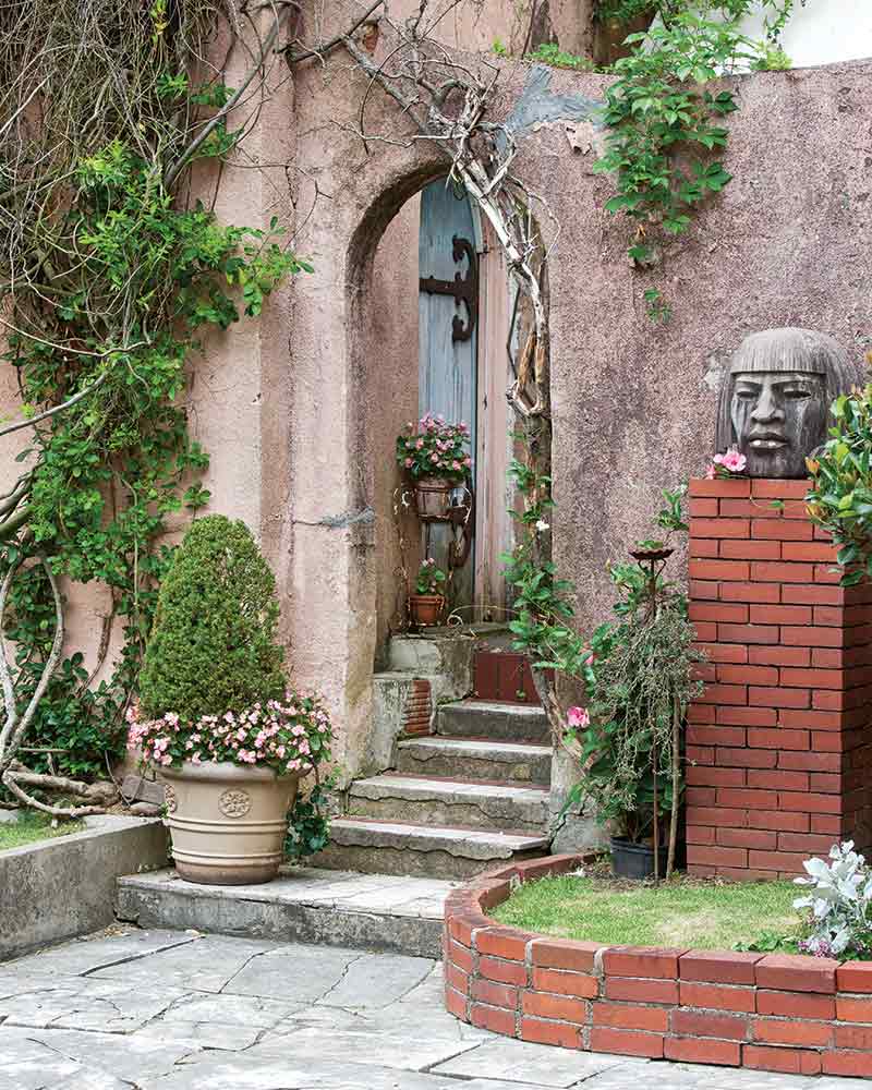 Stone stairs leading to an archway in a garden with Italian influences.