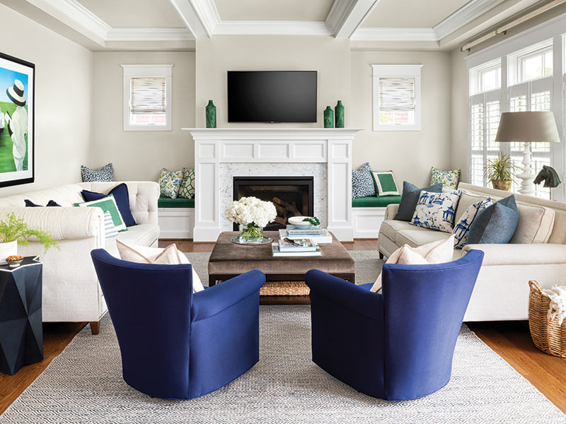 A family room with two navy armchairs facing a tv mounted over the fireplace.
