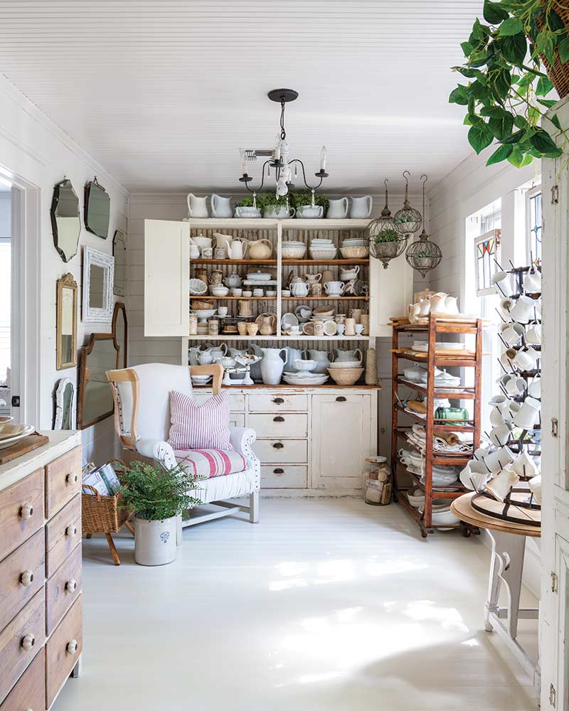 A white, vintage-style sunroom featuring an assortment of collectibles.