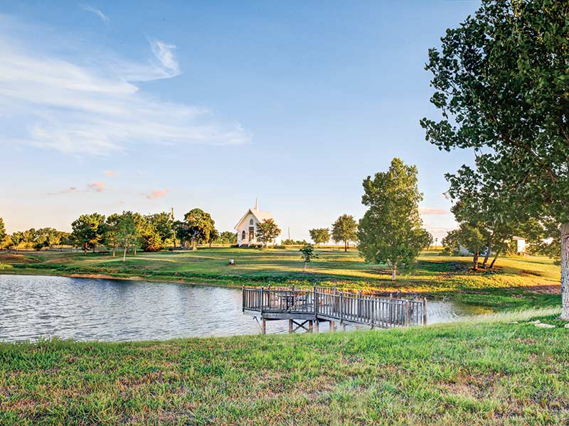 A pond and rolling hills overlooking a renovated Texas chapel.