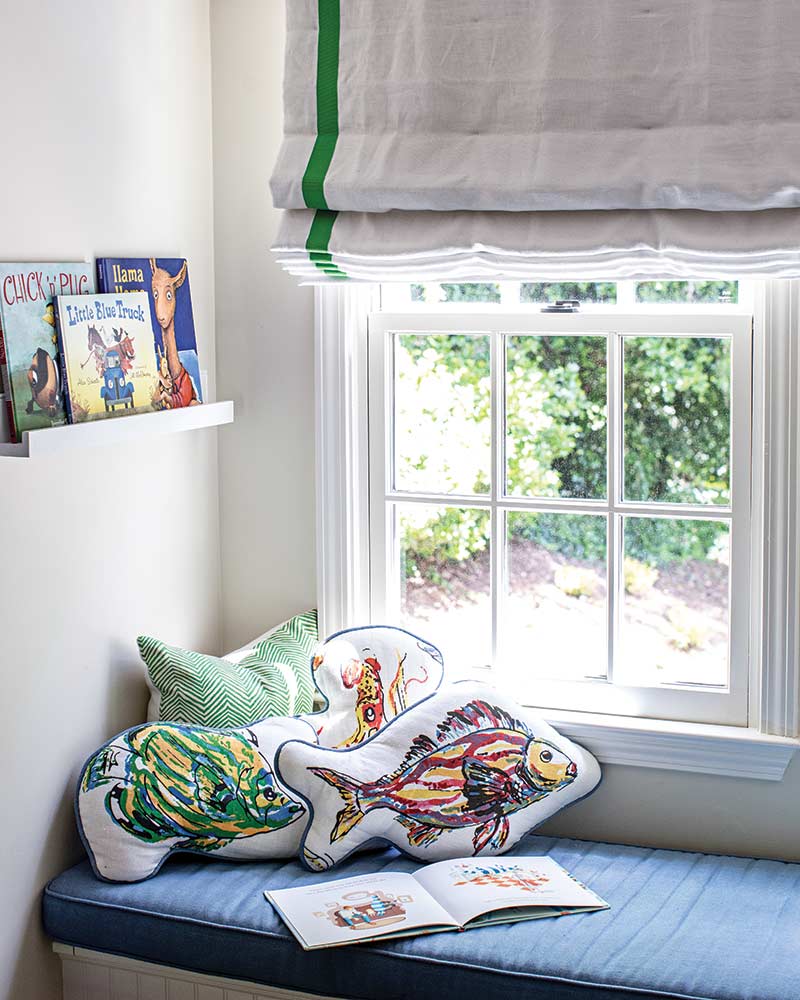 A window seat with fish pillows and a shelf for books.