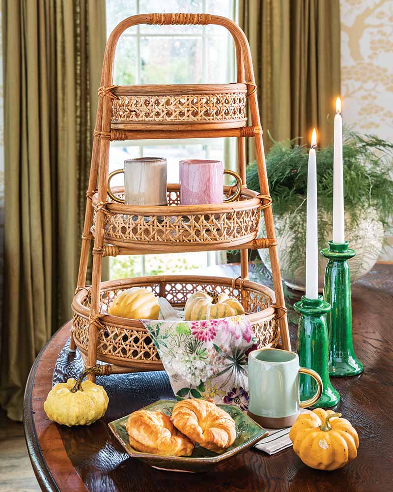 A tabletop vignette with a rattan tiered basket and green candle holders.
