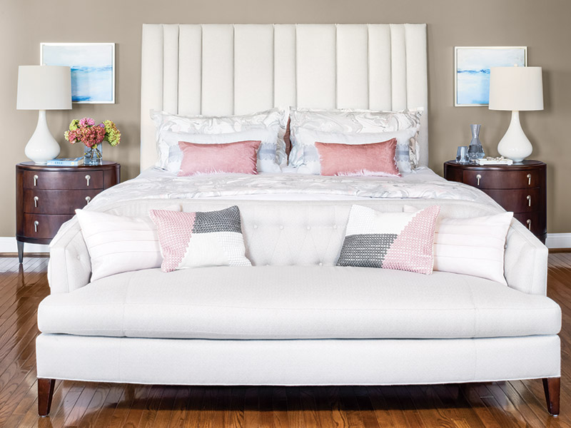 A white bed with light pink accessories.
