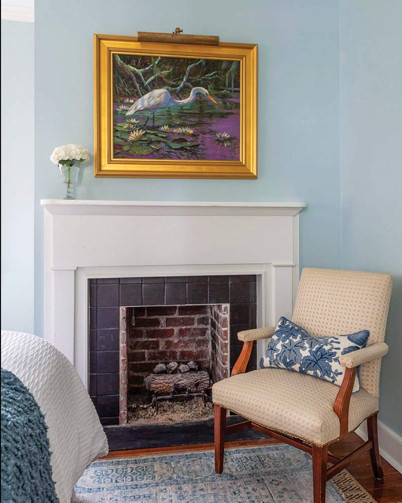 South Carolina Home - Bedroom corner with reading chair, fireplace, and heron portrait above mantle